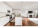 Bright, open-concept kitchen featuring white cabinetry, stainless steel appliances, granite countertops, and hardwood floors at 3231 Riverwood Way, Castle Rock, CO 80109