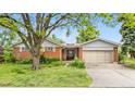 Charming single-story home featuring brick and siding, with an attached two-car garage and mature landscaping at 10330 Melody Dr, Northglenn, CO 80260