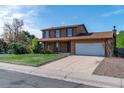 A two-story home with a brick facade, covered porch, large driveway, and a well-kept lawn at 11098 Fairfax Way, Thornton, CO 80233