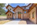 Charming stone exterior with a custom wood front door and manicured landscaping at 11790 Huckleberry Drive Dr, Franktown, CO 80116