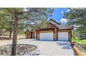 Stone home features a three-car garage, mature trees, and a circular driveway at 11790 Huckleberry Drive Dr, Franktown, CO 80116