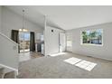 Bright living room with new carpet and high ceilings open to the kitchen and outdoor living space at 17593 E Temple Dr, Aurora, CO 80015