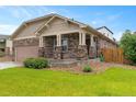 Single story home showcasing stone columns, covered porch, and lush lawn at 3838 Brush Rd, Castle Rock, CO 80108