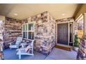 Inviting covered front porch with stone accents, seating, and a welcoming entryway at 3838 Brush Rd, Castle Rock, CO 80108