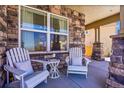 Comfortable seating on a charming front porch with stone details and large window at 3838 Brush Rd, Castle Rock, CO 80108