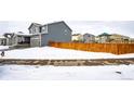 Landscaped backyard with wooden fence, partially covered by snow at 47387 Lilac Ave, Bennett, CO 80102