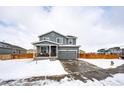 Two-story house with gray siding, attached garage, and covered porch at 47387 Lilac Ave, Bennett, CO 80102