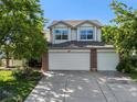 Inviting two-story home with a three-car garage, manicured lawn, and vibrant flower beds at 1010 Home Farm Cir, Denver, CO 80234