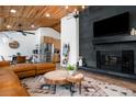 Cozy living room with a stone fireplace, modern light fixture, open layout, and a beautiful wood plank ceiling at 9034 Us Highway 285, Morrison, CO 80465