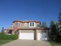 Two-story home with a 2-car garage, brick accents, and a well-manicured lawn on a sunny day at 518 Zircon Way, Superior, CO 80027