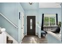 Inviting foyer with light blue walls, dark-stained front door, hardwood floors, and staircase at 9821 Bucknell Ct, Highlands Ranch, CO 80129