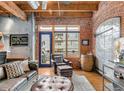 Living room boasts exposed brick walls, wood beams, and comfortable seating with an exterior view at 2960 Inca St # 317, Denver, CO 80202