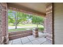 View from a covered front porch with brick columns, showcasing a lovely neighborhood scene at 6404 Silver Mesa Dr # E, Highlands Ranch, CO 80130