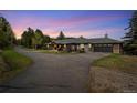 A ranch-style home featuring a two-car garage, lush landscaping, and scenic evening skies at 27436 Kennedy Gulch Rd, Conifer, CO 80433