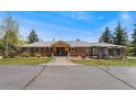 Charming brick ranch-style home featuring a welcoming front porch and pergola covered patio area at 27436 Kennedy Gulch Rd, Conifer, CO 80433