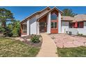 Inviting front entrance featuring colorful landscaping, a unique walkway, and a white facade with wooden accents at 6663 S Prescott Way, Littleton, CO 80120