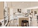 Bright white kitchen with stainless steel appliances, a large island with a breakfast bar, and modern light fixtures at 10472 Grizzly Gulch, Highlands Ranch, CO 80129