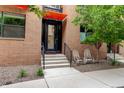 Charming brick townhouse featuring an orange awning, rocking chairs and well-manicured landscaping at 3030 Wilson Ct # 5, Denver, CO 80205
