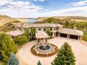 Stunning estate with circular driveway and fountain, set against a picturesque mountain and lake backdrop at 6729 Bear Point Trl, Golden, CO 80403
