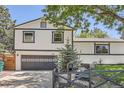 Two-story home showcasing a driveway and an inviting front entrance framed by mature trees and manicured landscaping at 1676 S Fairplay St, Aurora, CO 80012