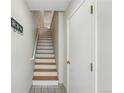 Interior staircase with white risers and wood treads adjacent to a white door at 1699 S Trenton St # 147, Denver, CO 80231