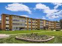 Full building exterior shot with a well-manicured lawn and vibrant flower beds under a blue sky at 9655 E Center Ave # 11D, Denver, CO 80247