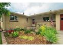 Charming brick home featuring a flower garden, a sitting area and an American flag at 1705 Lewis St, Lakewood, CO 80215