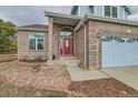 Close-up of the front entrance featuring a red door with decorative glass and brick accents at 18715 Wagon Trl, Mead, CO 80542
