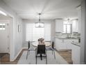 Bright dining area with new lighting next to a kitchen with white cabinetry and granite countertops at 863 S Dudley St, Lakewood, CO 80226