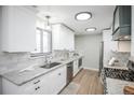 Updated kitchen with white cabinets, granite countertops, stainless steel appliances, and wooden floors at 863 S Dudley St, Lakewood, CO 80226