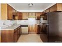 Traditional kitchen featuring wood cabinets, stainless steel sink, and black refrigerator at 655 S Alton Way # 8D, Denver, CO 80247