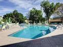 Bright, sunny pool area surrounded by trees, lounge chairs, and umbrellas at 655 S Alton Way # 8D, Denver, CO 80247