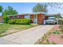 Single-story brick home featuring a covered parking area and a spacious cracked driveway at 245 S 13Th Ave, Brighton, CO 80601