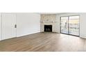 Bright living room featuring a stone fireplace, wood floors, and sliding glass doors to the balcony at 18302 E Kepner Pl # 207, Aurora, CO 80017