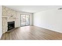 A living room with stone fireplace, wood floors, and sliding glass doors to the balcony at 18302 E Kepner Pl # 207, Aurora, CO 80017