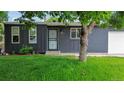Close-up of the house's gray brick facade with a green lawn, trees, and dark trim around the windows and door at 5170 Deephaven Ct, Denver, CO 80239