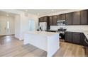 Modern kitchen with stainless steel appliances, island, and dark cabinets at 683 N Deer Park St, Watkins, CO 80137