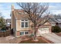 Side view of a two-story home with a brick foundation, a two-car garage, and a landscaped yard at 4334 Lisbon St, Denver, CO 80249