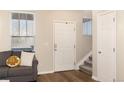 Bright foyer with wood floors, a white front door, and a staircase leading upstairs near a cozy couch at 22725 E Ottawa Pl, Aurora, CO 80016