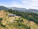 Scenic view of estate-style home with large land parcel nestled on a mountainside surrounded by lush greenery at 18844 Ute Vista Trl, Morrison, CO 80465