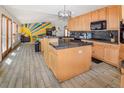 Open kitchen with island, wood cabinets, and gray tile floors extending to living area at 951 S Fulton St, Aurora, CO 80247