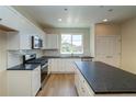 Bright kitchen with white cabinets, black countertops, and stainless steel appliances at 23951 E 40Th Ave, Aurora, CO 80019