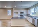 Open kitchen with island, white cabinets, stainless steel appliances, and bright natural light at 23951 E 40Th Ave, Aurora, CO 80019