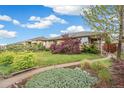 Brick home featuring a landscaped front yard with mature trees and a walkway to the covered porch at 3620 Fairfax St, Denver, CO 80207