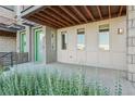 Outdoor patio with a view of manicured greenery, a green door, and warm lighting at 5668 Galena St, Denver, CO 80238