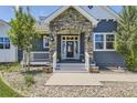 Charming front porch with stone accents, stylish lighting, and decorative plants at 41975 Muirfield Loop, Elizabeth, CO 80107