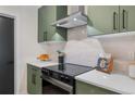 Modern kitchen featuring stainless hood, glossy subway tile backsplash, and green cabinetry with black hardware at 3275 Lawrence St, Denver, CO 80205