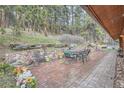 Backyard brick patio with dining set, sitting area, and surrounding greenery at 21191 Pleasant Park Rd, Conifer, CO 80433