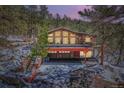 Exterior view of stone-clad home with a three-car garage and a spacious outdoor deck at 21191 Pleasant Park Rd, Conifer, CO 80433