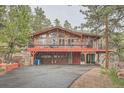 Rustic home featuring a wooden deck and garage space underneath in wooded area at 21191 Pleasant Park Rd, Conifer, CO 80433